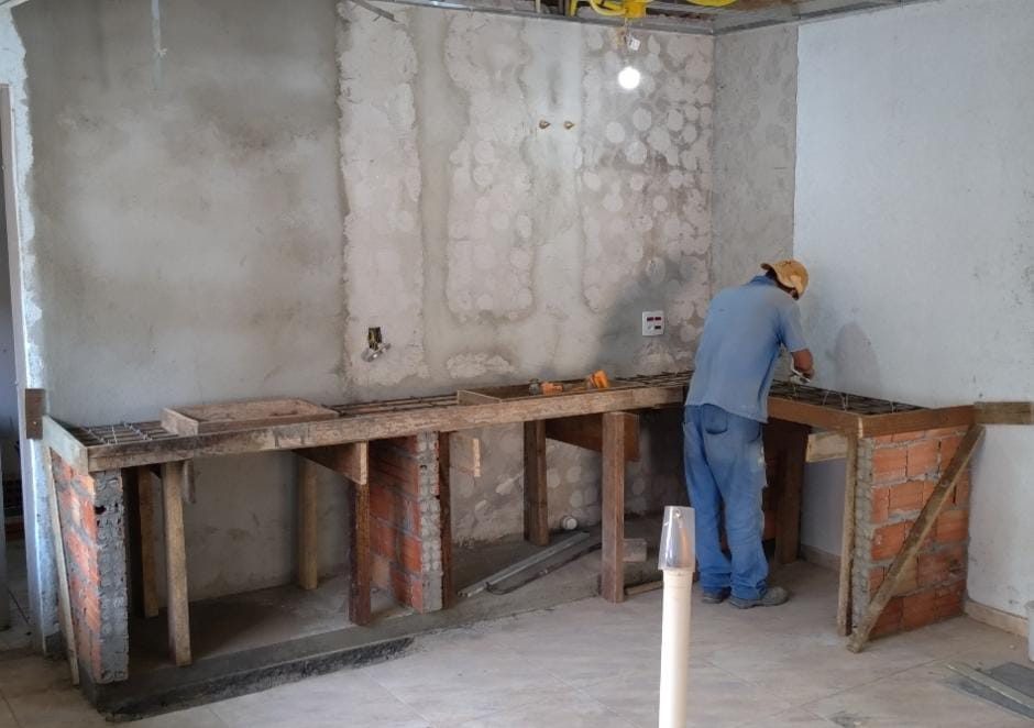 João montando a forma de madeira e a ferragem do tampo de uma bancada sobre pilaretes de tijolo