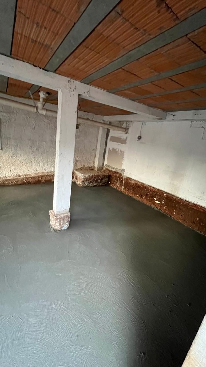 Contrapiso recém feito embaixo de uma laje de tijolo, com pilar no meio
